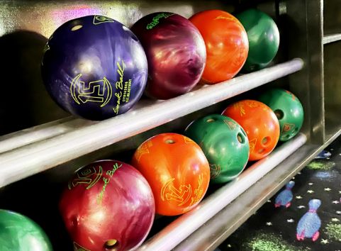 Angled shot of assorted bowling balls in the ball rack